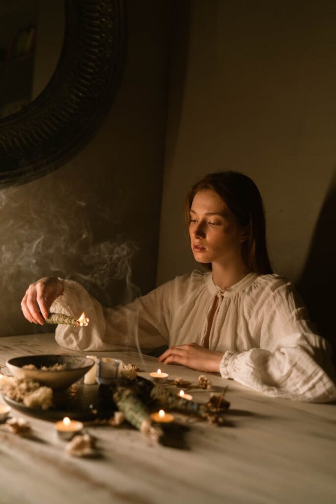 Caucasian woman in white blouse with candles and sage, creating a serene atmosphere.